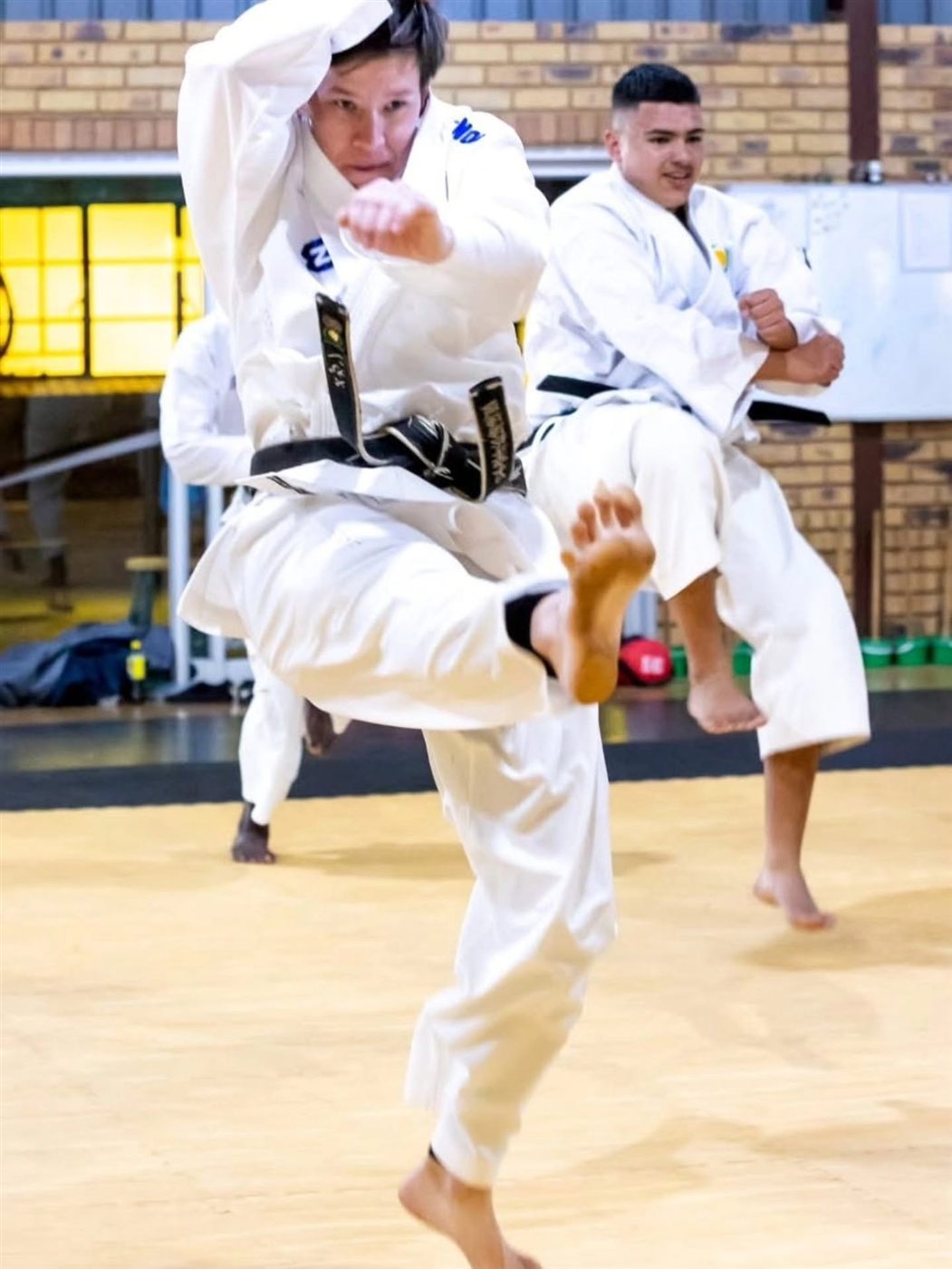 Sensei Meghan Smit and a student mid-kick at a karate event